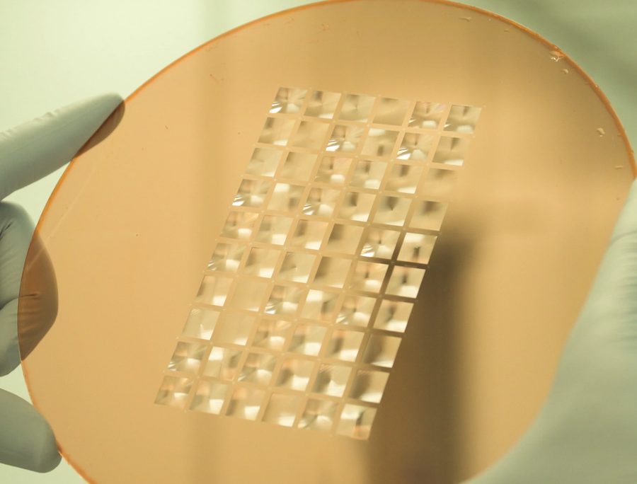 A wafer with an array of fabricated diffractive lenses, held in a gloved hand.